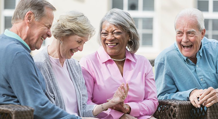 Multiracial senior friends sitting outdoors on patio talking