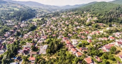 test-drive-a-neighborhood-with-aerial-view-of-small-town-with-many-hills-and-forest-surrounding-it